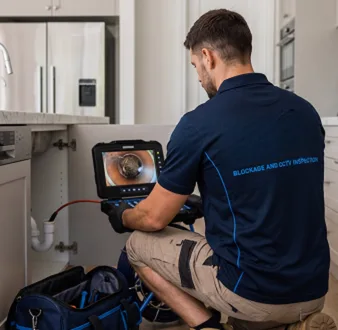 Plumber clearing a blocked toilet in a Manly bathroom
